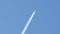 Distant passenger jet plane flying on high altitude on clear blue sky leaving white smoke trace of contrail behind. Air