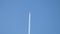 Distant passenger jet plane flying on high altitude on clear blue sky leaving white smoke trace of contrail behind. Air