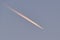 Distant passenger jet plane flying on high altitude on clear blue sky leaving white smoke trace of contrail behind. Air