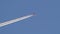 Distant passenger jet plane flying on high altitude on clear blue sky leaving white smoke trace of contrail behind. Air