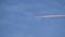 Distant passenger jet plane flying on high altitude on clear blue sky leaving white smoke trace of contrail behind. Air