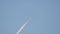 Distant passenger jet plane flying on high altitude on clear blue sky leaving white smoke trace of contrail behind. Air
