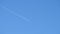 Distant passenger jet plane flying on high altitude on clear blue sky leaving white smoke trace of contrail behind. Air