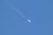 Distant passenger jet plane flying on high altitude on clear blue sky leaving white smoke trace of contrail behind. Air