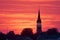 distant silhouette of a church steeple against a crimson sunset