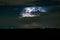 Distant supercell thunderstorm is lit by lightning at night