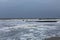 Distant surfers in a storm, heavy surf and sea foam on a sandy coastline