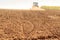 distant tractor leaves fresh track on wet ploughed field