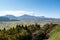 Distant view of Aso valley and mountain ridge with Mount Aso volcano venting steam on sunny autumn day, Japan.