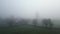 Distant view of a country house in the fields in a foggy morning