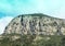 Distant view of a cross atop an mountain with sheer cliffs ouside Sorrento, Italy