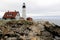 Distant view of Portland Head lighthouse, with stormy skies and rough seas, Maine,2016