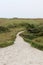 Distant view on a sandy foot path under a blue sky on the northern sea island juist germany