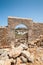 Distant view through stone arch opening at Lindos Town and Castle with ancient ruins of the Acropolis on sunny warm day. Island of