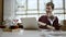 Distant view of a young businessman sitting at a table in a cafe using iphone and laughing, watching the passersby