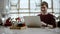 Distant view of a young businessman sitting at a table in a cafe using iphone and laughing, watching the passersby