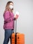 Distraught girl with a medical mask on her face is waiting for a canceled flight due to a coronavirus