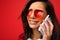 Distraught girl on a red background speaks on phone, close-up