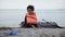 Distressed teen girl in life jacket sits near boat, refugee survived boat crash