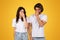 Distressed young couple in white shirts pinching their noses, displaying expressions of disgust