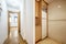 Distributor corridor of a house with an oak wooden corridor, access to a small kitchen with light wood furniture and a white