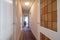 Distributor corridor of an urban residential house with white woodwork with leaded windows and parquet floors with narrow rugs