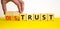 Distrust or trust symbol. Businessman turns wooden cubes, changes words `distrust` to `trust`. Beautiful yellow table, white