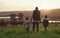 Ditch the media, go and make lasting memories. Rearview shot of a man and his two adorable children exploring a farm.