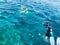 Divers in black diving waterproof suits with shiny metal aluminum canisters float, immerse in blue sea water on vacation, a sea cr