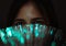 Diverse Asian girl looks through futuristic teal coloured bokeh - Millennial woman looking at camera with advanced fibre