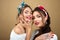 Diverse beauty, fashion: portrait of two happy smiling young girls in bright headbands posing isolated on beige background