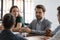 Diverse business team sitting in meeting room listening to colleague