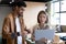 Diverse businesswoman and businesswoman using laptop and smartphone in office