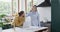 Diverse couple using laptop and smartphone in kitchen at home, in slow motion