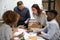 Diverse employees team discussing project strategy, reading documents in boardroom