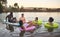 Diverse friend group floating on lake water, having fun in nature and bonding on a vacation in countryside sunset with