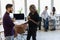 Diverse friends two coworkers standing at office distracted from work take break drink coffee having informal talk. Boss employee