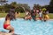 Diverse group of friends taking photo and sitting at the poolside