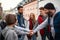 Diverse group of happy community service volunteers stacking hands together outdoors in street