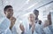 Diverse group of happy scientists clapping hands while writing and planning together on a board at work. Team of