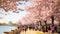 A diverse group of individuals walks together down a scenic path next to a beautiful body of water, Cherry blossom festival in