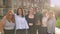 Diverse group of laughing caucasian girls standing near and holding with proud outside in daytime