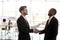 Diverse laughing colleagues handshake in company office hallway