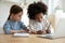 Diverse little sisters study online on laptop together