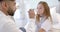 Diverse male doctor checking eyes of girl patient in hospital bed with penlight, slow motion