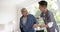 Diverse male doctor helping senior male patient standing up at home, slow motion