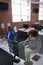 Diverse male and female colleagues sitting in front of computers separated by sneeze shields