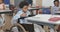 Diverse male teacher and happy schoolboy in wheelchair writing in classroom at elementary school