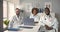 Diverse medical colleagues sitting at desk chatting and laughing in clinic office