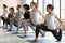 Diverse people practicing yoga, standing in anjaneyasana pose in row